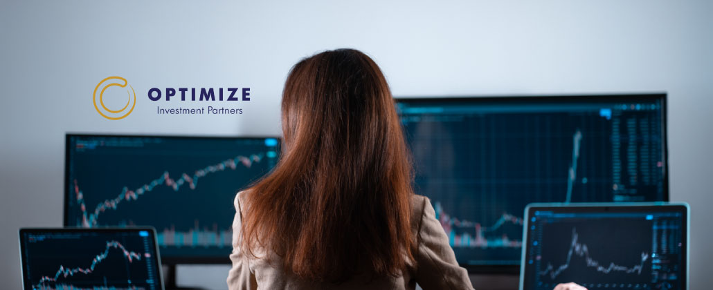 Mulher sentada numa secretária cheia de computadores a investir nos fundos de investimento Optimize.